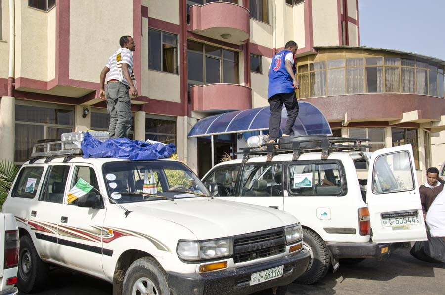 Ethiopian tour guides pack luggage on roof of Toyota Landcruisers