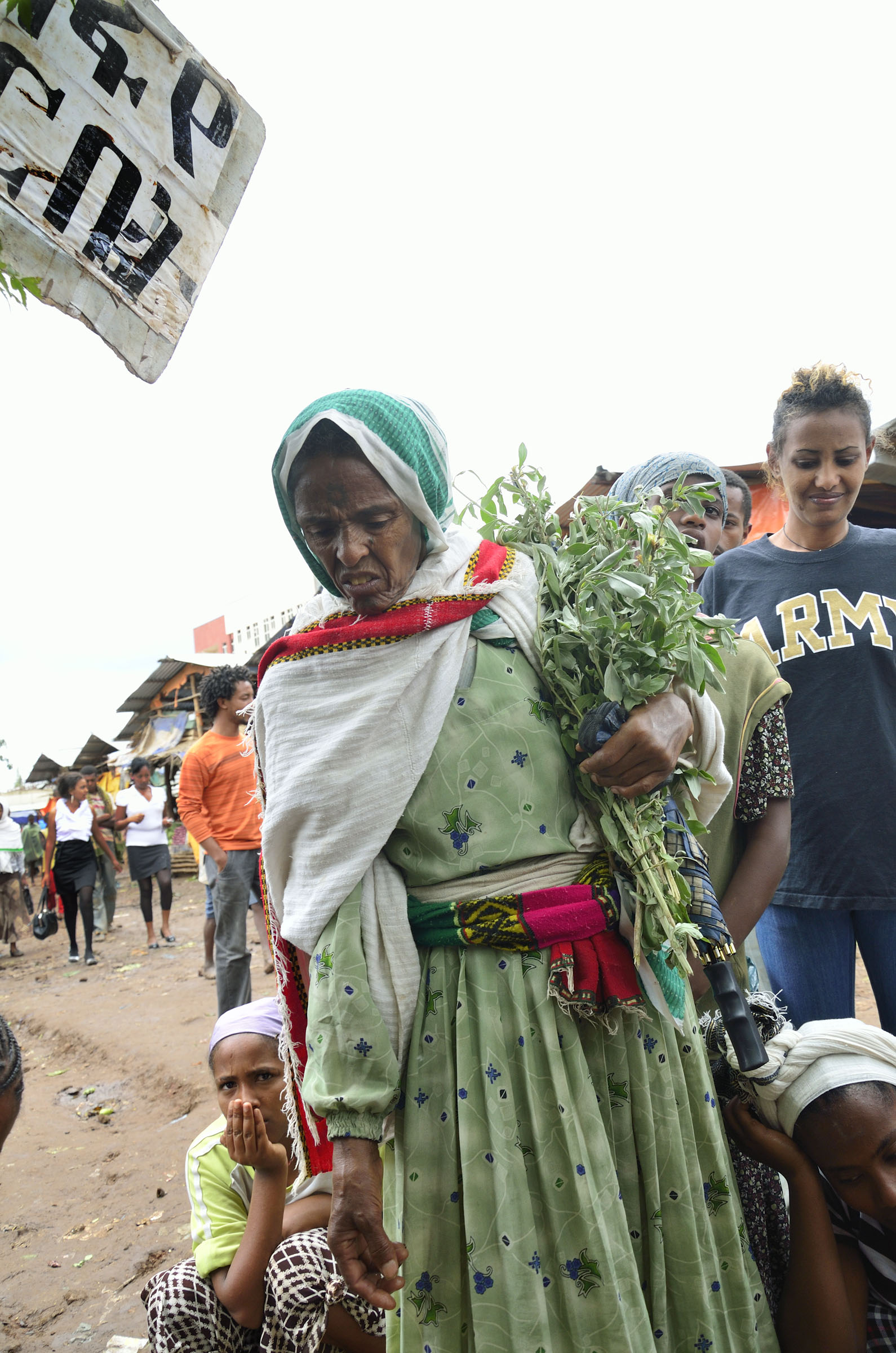 Ethiopian woman in green dress carrying herbs